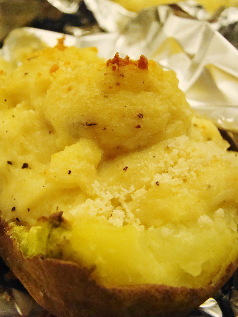 Batatas grandes inteiras assando na grade do forno