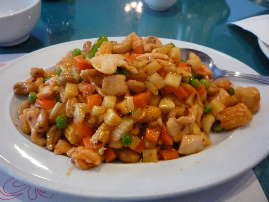 Cubos de frango dourados sendo refogados em wok com molho de shoyu