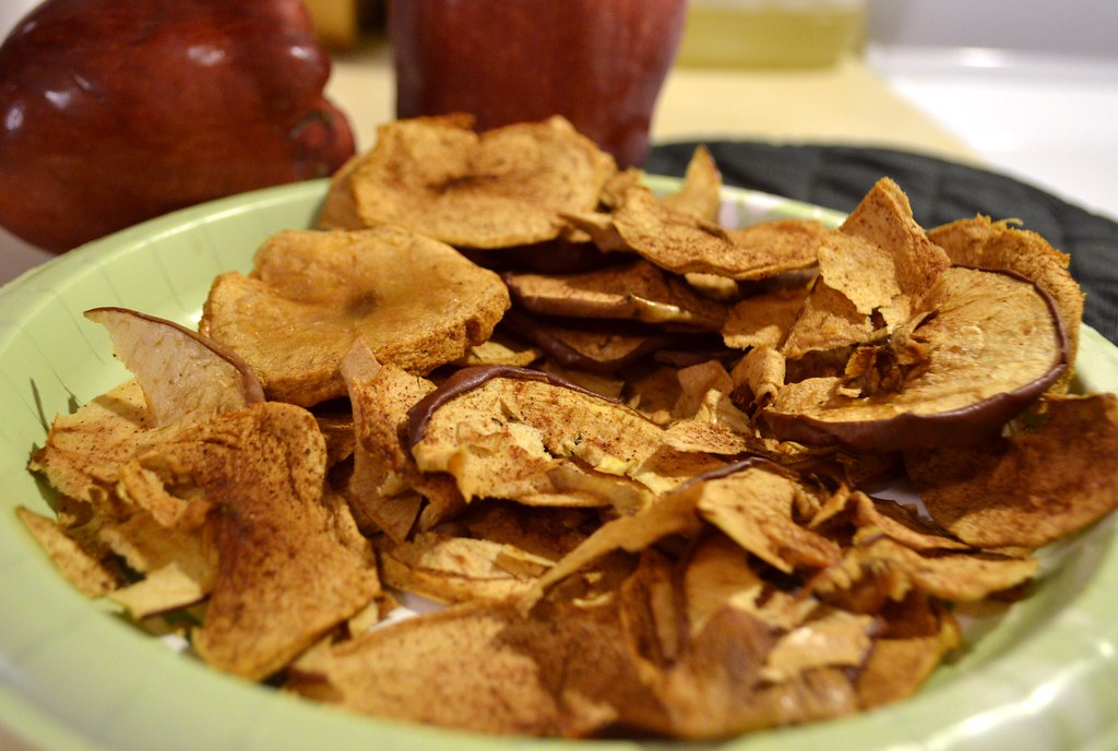 Chips de maçã com canela ao lado de maçãs frescas
