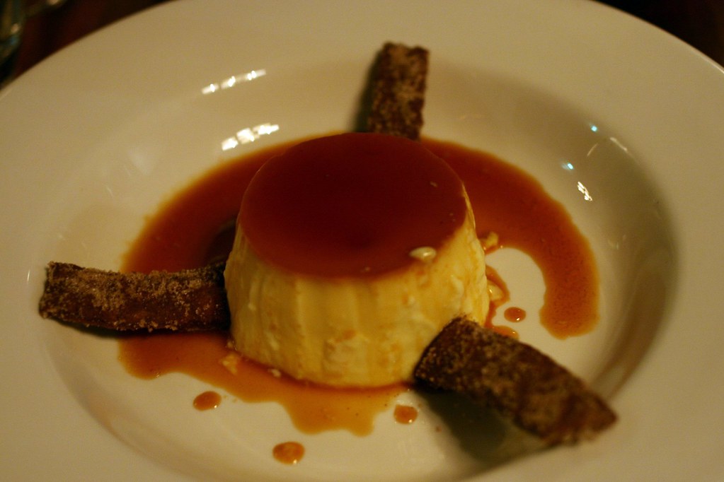 Pudim de leite com calda de caramelo em prato branco